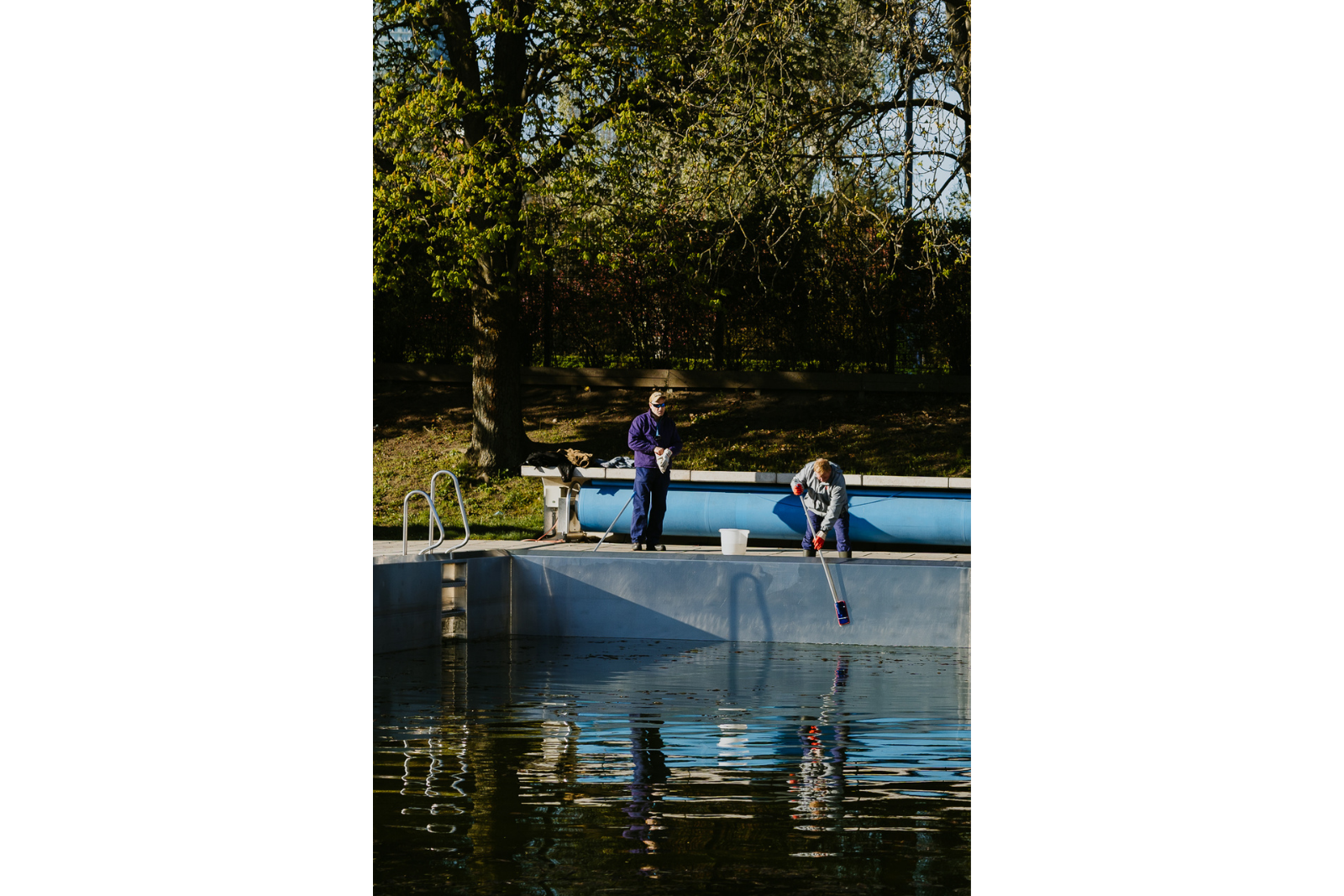 Mitarbeiter des Strandbads Alte Donau fischen mit Kescher Verunreinigungen aus dem Schwimmbecken. Fotoprojekt, Fotoreportage Wien