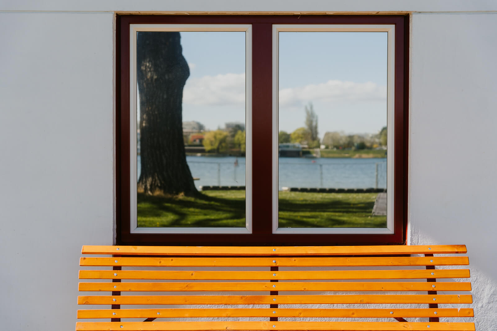 Außenansicht des Badehauses im Strandbad Alte Donau. Im Fenster spiegelt sich die Alte Donau.