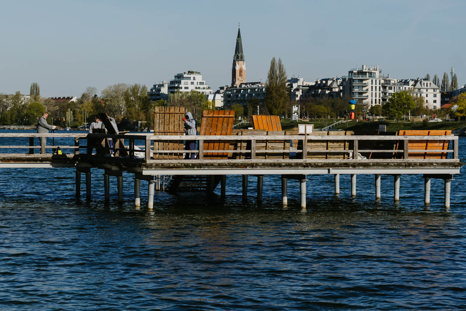 Mitarbeiter des Strandbads transportieren Holzliegeflächen über den Steg.