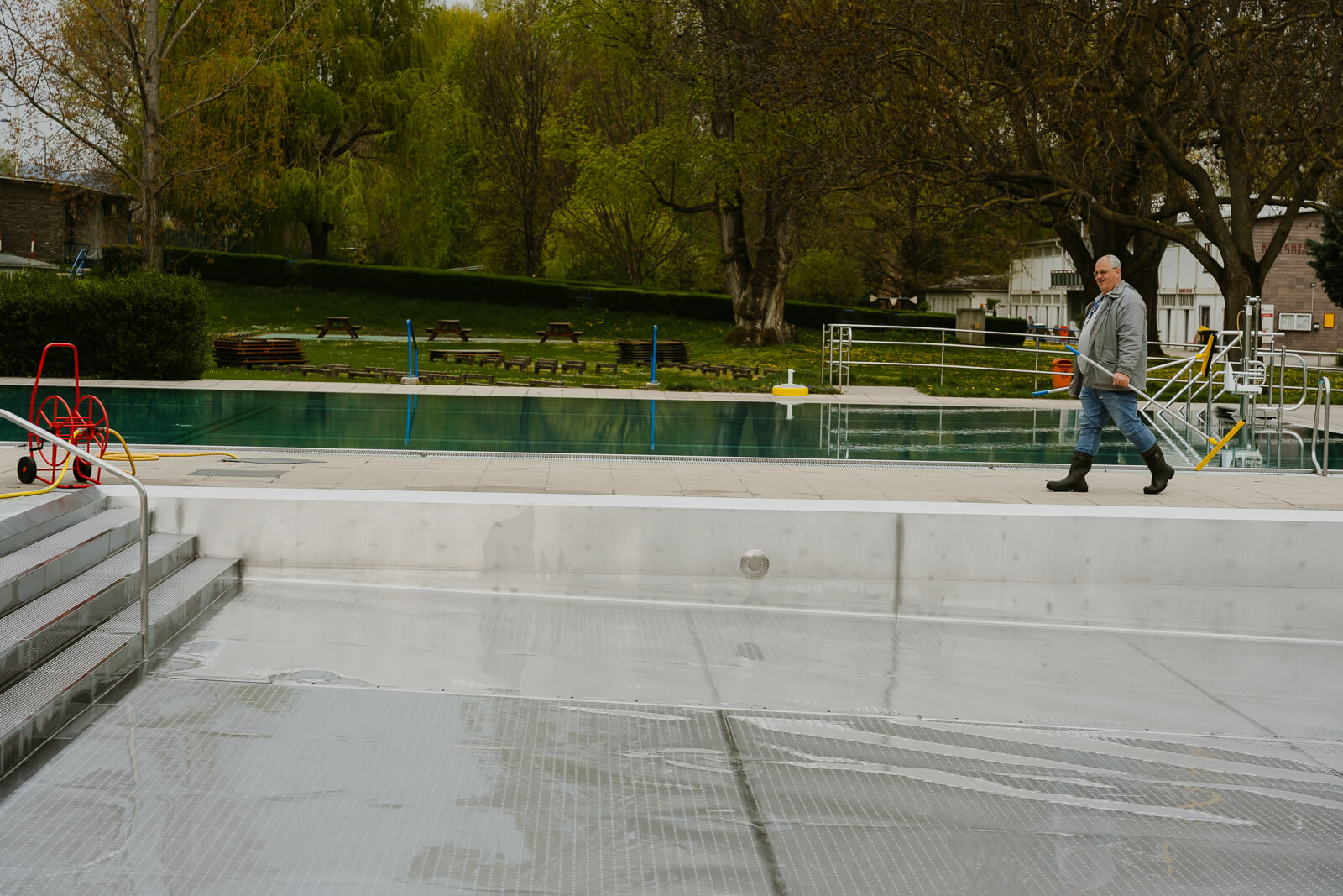 Ein Mitarbeiter geht am Beckenrand entlang, zu sehen ist außerdem das leere Schwimmbecken.