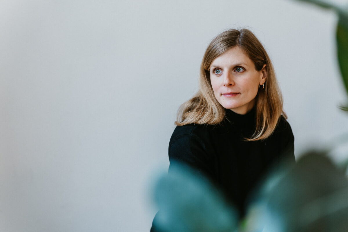 Frau blickt zur Seite mit unscharfem Vordergrund, ruhiges Portrait im Innenraum – Personal Branding Fotografie Wien und Niederösterreich