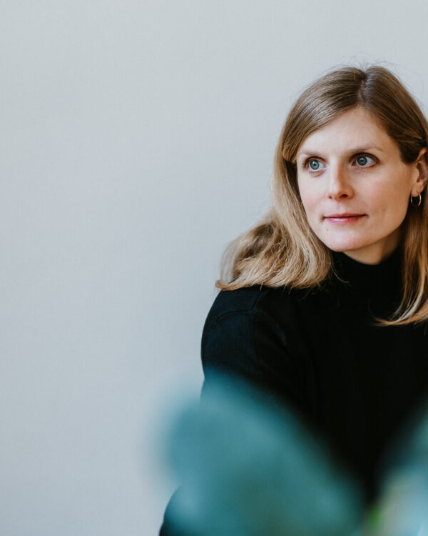 Frau blickt zur Seite mit unscharfem Vordergrund, ruhiges Portrait im Innenraum – Personal Branding Fotografie Wien und Niederösterreich