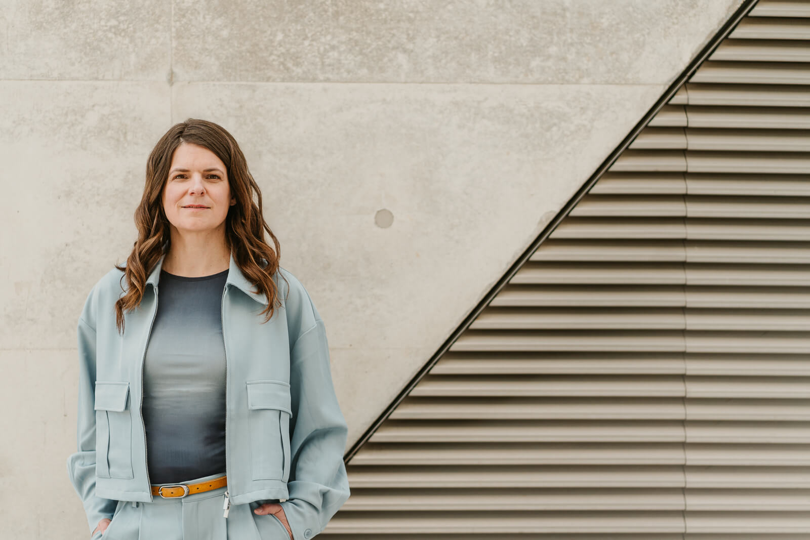 Frau steht vor moderner Architektur mit klaren Linien, ruhiges Business Portrait im Außenbereich – Personal Branding Fotografie Wien und Niederösterreich